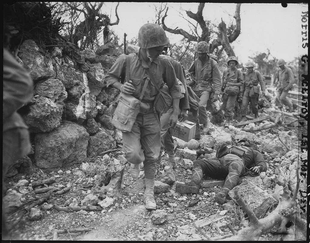Marines pass through a small village where Japanese soldiers lay dead. Okinawa, April 1945. - NARA -