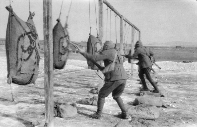 Three Australian soldiers wearing gas masks practice bayonet tactics in England during 1916 or 1917.jpg